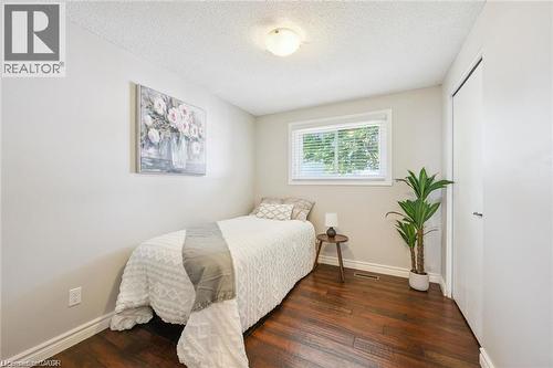 Bright secondary bedroom showcasing hardwood flooring, large window with natural light, and fresh neutral finishes - 659 Glen Forrest Boulevard, Waterloo, ON - Indoor Photo Showing Bedroom