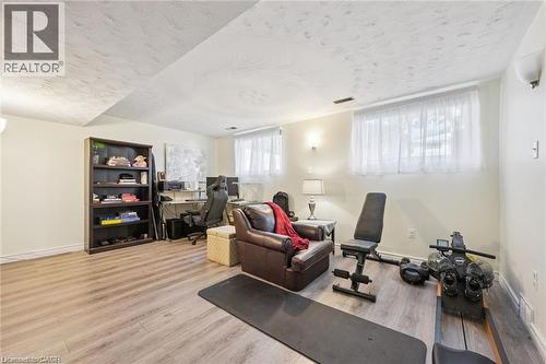 Finished basement recreation space featuring engineered wood-finish flooring, recessed ceiling lighting, and large windows with sheer treatments - 659 Glen Forrest Boulevard, Waterloo, ON - Indoor
