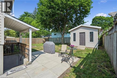 Expansive backyard oasis featuring a mature shade tree, manicured lawn, and multiple entertaining spaces including a covered patio with wooden railings and a detached accessory dwelling - 659 Glen Forrest Boulevard, Waterloo, ON - Outdoor With Deck Patio Veranda
