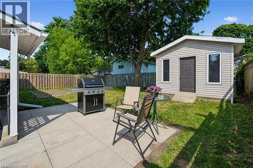 Expansive backyard featuring a concrete patio, mature trees, wood fence, and an outdoor shed with siding and multiple windows - 659 Glen Forrest Boulevard, Waterloo, ON - Outdoor
