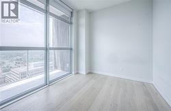 Floor-to-ceiling windows, light wood-finish flooring, white painted walls, and roller shades - 