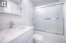 White tiled bathroom featuring a vanity with an integrated sink, polished chrome faucet, and a wall-mounted medicine cabinet - 