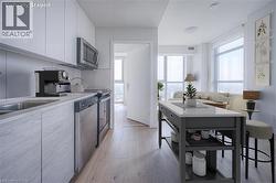 Modern kitchen featuring light wood-finish cabinetry, stainless steel appliances, and wood-finish flooring - 
