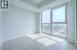 Expansive window wall with city backdrop, roller shades, light wood-finish flooring, and white painted walls - 