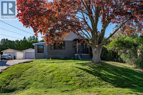 Property features a gray exterior with contrasting light gray siding, multiple windows, and a mature tree - 1041 Shepherd'S Drive, Burlington, ON - Outdoor