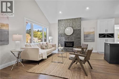 Vaulted ceiling, stone-clad fireplace, wood-finish flooring, built-in cabinetry, and large picture windows - 1041 Shepherd'S Drive, Burlington, ON - Indoor Photo Showing Living Room With Fireplace