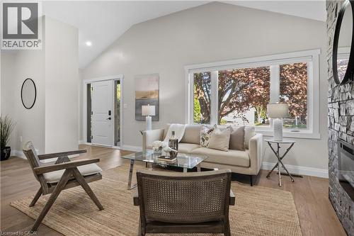 Vaulted ceiling, wood-finish flooring, stone-clad fireplace, large window, and white interior door - 1041 Shepherd'S Drive, Burlington, ON - Indoor Photo Showing Living Room