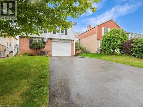 Brick and siding exterior with an attached garage, paved driveway, and established front landscaping - 128 Macatee Place, Cambridge, ON - Outdoor