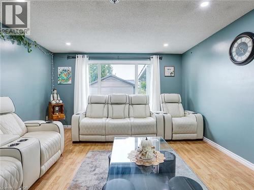 Wood-finish flooring, recessed lighting, and a large window with white curtains - 128 Macatee Place, Cambridge, ON - Indoor Photo Showing Living Room