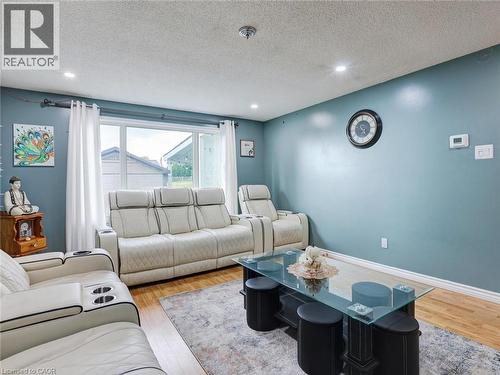 Sophisticated living room featuring soft blue-gray walls, recessed ceiling lighting, and wood-finish flooring - 128 Macatee Place, Cambridge, ON - Indoor Photo Showing Living Room
