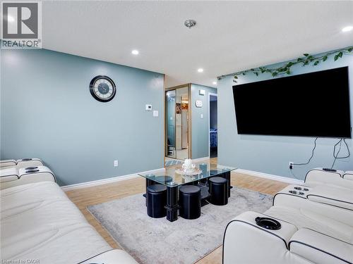 Finished Basement Recreation Room featuring recessed ceiling lighting, light wood-finish flooring, soft area rug, wall-mounted flat-screen television, built-in seating with storage ottomans, and a lar - 128 Macatee Place, Cambridge, ON - Indoor