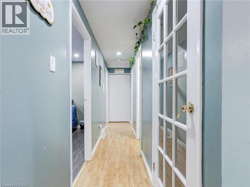 Hallway with wood-finish flooring, recessed lighting, and a white French door with a brass handle - 128 Macatee Place, Cambridge, ON - Indoor Photo Showing Other Room