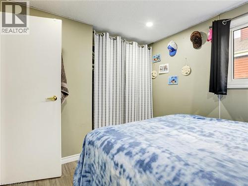Comfortable bedroom featuring soft blue patterned bedding, wood-finish flooring, and neutral walls - 128 Macatee Place, Cambridge, ON - Indoor Photo Showing Bedroom