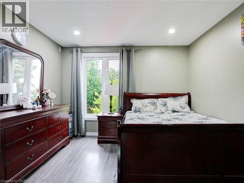 Spacious primary bedroom featuring rich wood furnishings, recessed ceiling lighting, and direct access to a private glass-door balcony overlooking mature landscaping - 128 Macatee Place, Cambridge, ON - Indoor Photo Showing Bedroom