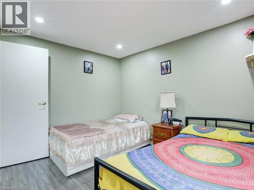 Bright, light-filled bedroom featuring recessed ceiling lighting, soft green walls, wood-finish flooring, and two beds with coordinating bedding - 128 Macatee Place, Cambridge, ON - Indoor Photo Showing Bedroom