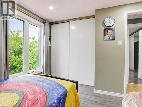 Bright bedroom retreat featuring expansive glass doors framed in natural wood trim, abundant natural light, and hardwood flooring - 128 Macatee Place, Cambridge, ON - Indoor Photo Showing Bedroom