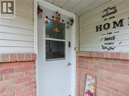 Welcoming entry featuring a white-painted steel door with window insert, brick facade with contrasting horizontal siding, and decorative seasonal accents above the entrance - 128 Macatee Place, Cambridge, ON - Outdoor With Exterior