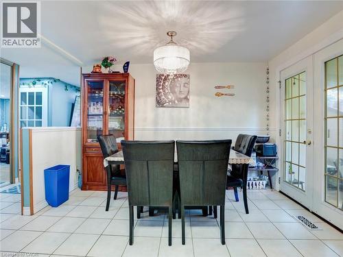 White tile flooring, wainscoting detail, ceiling-mounted light fixture, and French doors with grid-patterned glass - 128 Macatee Place, Cambridge, ON - Indoor Photo Showing Dining Room