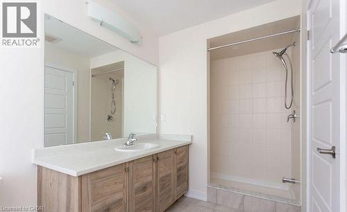Wood-finish vanity with a white countertop, undermount sink, and polished chrome faucet - 16 Monteith Drive, Brantford, ON - Indoor Photo Showing Bathroom