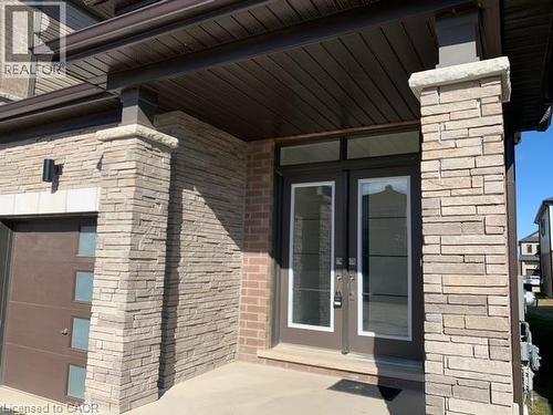 Stone veneer facade, covered entry, double entry doors, transom window, and integrated garage door - 16 Monteith Drive, Brantford, ON - Outdoor With Exterior