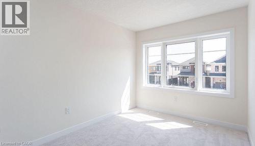 Neutral wall color, carpet flooring, and a large three-panel window - 16 Monteith Drive, Brantford, ON - Indoor Photo Showing Other Room