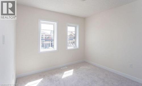 Neutral-toned wall paint, two bright windows, and light gray carpeting - 16 Monteith Drive, Brantford, ON - Indoor Photo Showing Other Room