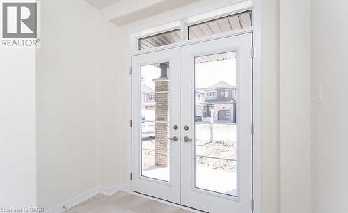 Double entry doors with transom window, light-toned walls, and neutral-toned floor tile - 16 Monteith Drive, Brantford, ON - Indoor Photo Showing Other Room
