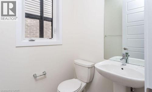 White pedestal sink with chrome faucet, toilet, and a window with horizontal blinds - 16 Monteith Drive, Brantford, ON - Indoor Photo Showing Bathroom