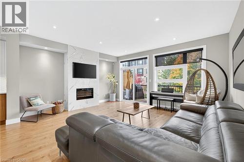 Open-concept living area featuring wood-finish flooring and a contemporary fireplace with a stone-finish surround - 60 Arkell Road Unit# 57, Guelph, ON - Indoor Photo Showing Living Room With Fireplace