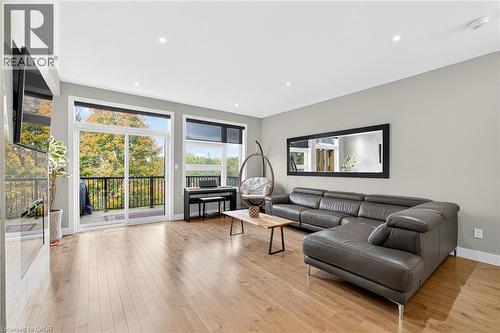 Hardwood flooring, recessed lighting, expansive sliding glass doors, black railing balcony, and a large wall-mounted mirror - 60 Arkell Road Unit# 57, Guelph, ON - Indoor Photo Showing Living Room