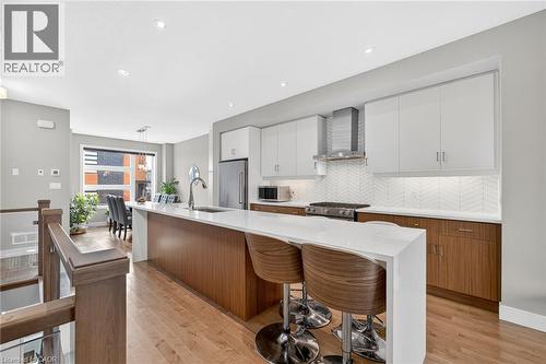 Open-concept kitchen with a waterfall island, stainless steel appliances, wood-finish flooring, and two-tone cabinetry - 60 Arkell Road Unit# 57, Guelph, ON - Indoor Photo Showing Kitchen With Upgraded Kitchen