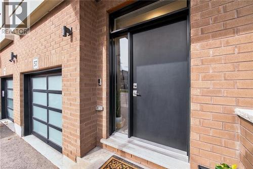 Brick exterior featuring a solid entry door with sidelight, transom window, and a modern garage door with frosted panels - 60 Arkell Road Unit# 57, Guelph, ON - Outdoor With Exterior