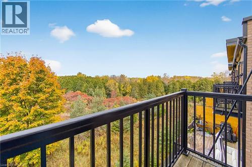 Wood-finish balcony with black metal railings overlooking a dense tree line - 60 Arkell Road Unit# 57, Guelph, ON - Outdoor With Balcony