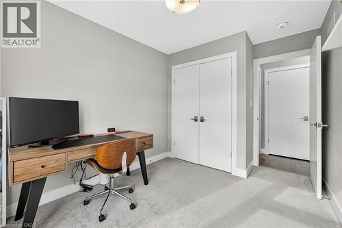 Plush carpet flooring, double-door closet with satin nickel hardware, flush-mount ceiling light fixture, and light gray wall paint - 60 Arkell Road Unit# 57, Guelph, ON - Indoor Photo Showing Office