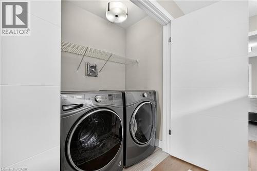 Dedicated laundry space with wire shelving, modern flush mount lighting, and wood-finish flooring - 60 Arkell Road Unit# 57, Guelph, ON - Indoor Photo Showing Laundry Room