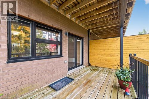 Private wood deck featuring a covered area, black metal railings, a brick exterior wall, and a sliding glass door - 60 Arkell Road Unit# 57, Guelph, ON - Outdoor With Deck Patio Veranda With Exterior