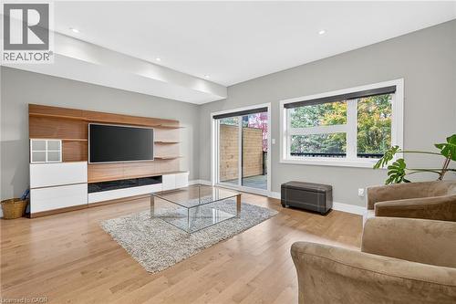 Recessed lighting, wood-finish flooring, built-in media console with shelving, sliding glass door, and large window - 60 Arkell Road Unit# 57, Guelph, ON - Indoor Photo Showing Living Room