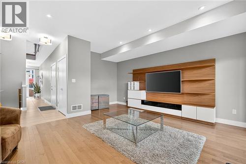 Wood-finish flooring throughout, complemented by a contemporary built-in media center with wood-tone accents and white cabinetry - 60 Arkell Road Unit# 57, Guelph, ON - Indoor Photo Showing Living Room