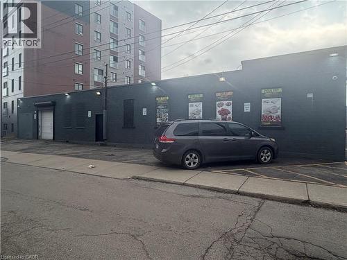 Dark-toned brick exterior with multiple windows and a roll-up door - 10 Sanford Avenue N, Hamilton, ON 