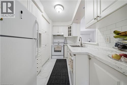 Kitchen featuring white cabinetry, white subway tile backsplash, light-colored countertops, and stainless steel sink - 230 Sunset Boulevard, Cambridge, ON - Indoor Photo Showing Kitchen With Double Sink