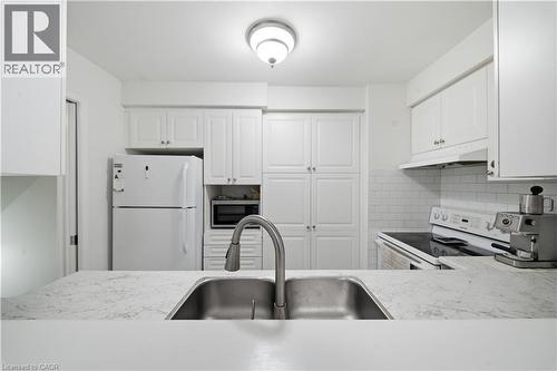 Stainless steel sink with a pull-down faucet, light-toned countertop, white subway tile backsplash, white cabinetry, and white appliances - 230 Sunset Boulevard, Cambridge, ON - Indoor Photo Showing Kitchen With Double Sink
