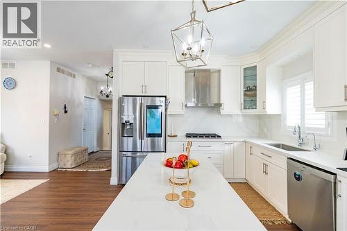 Gourmet kitchen featuring a central island, stainless steel appliances, white cabinetry, and wood-finish flooring - 122 Iron Gate Street, Kitchener, ON - Indoor Photo Showing Kitchen With Stainless Steel Kitchen With Upgraded Kitchen