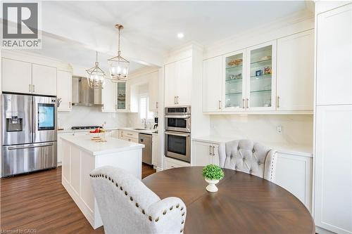 White cabinetry with gold-tone hardware, stainless steel appliances, a central island, patterned backsplash, and wood-finish flooring - 122 Iron Gate Street, Kitchener, ON - Indoor