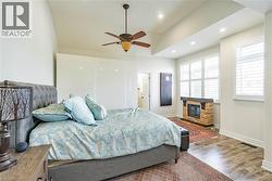 Vaulted ceiling, ceiling fan, recessed lighting, wood-finish flooring, and stone-clad fireplace - 