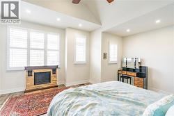 Vaulted ceiling with recessed lighting, stone-clad fireplace, wood-finish flooring, and multiple windows with plantation shutters - 