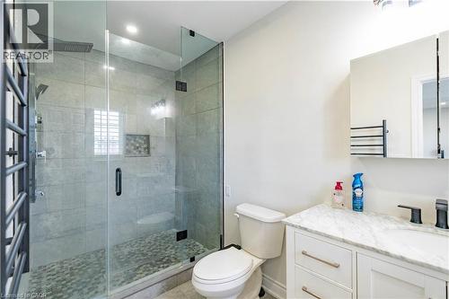Glass-enclosed shower with pebble-finish flooring, built-in shelving, and a rain shower head - 122 Iron Gate Street, Kitchener, ON - Indoor Photo Showing Bathroom