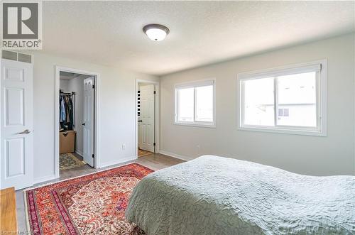 Bright interior with two windows, wood-finish flooring, recessed lighting, and a walk-in closet - 122 Iron Gate Street, Kitchener, ON - Indoor Photo Showing Bedroom