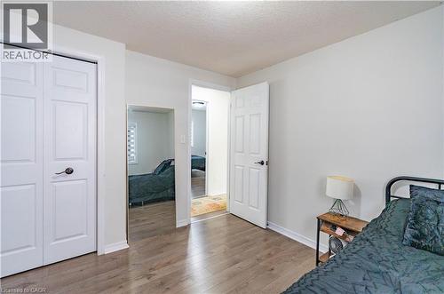 White interior walls, wood-finish flooring, white bi-fold closet doors, white six-panel door, and a full-length wall-mounted mirror - 122 Iron Gate Street, Kitchener, ON - Indoor Photo Showing Bedroom