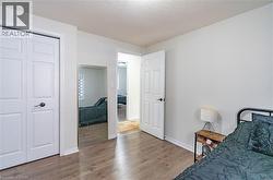 White interior walls, wood-finish flooring, white bi-fold closet doors, white six-panel door, and a full-length wall-mounted mirror - 
