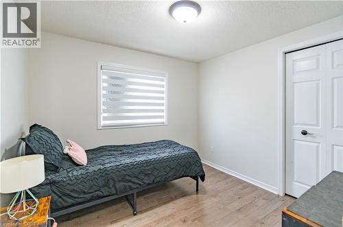 Wood-finish flooring, white walls, flush mount ceiling light, window with blinds, and white bi-fold closet doors - 122 Iron Gate Street, Kitchener, ON - Indoor Photo Showing Bedroom